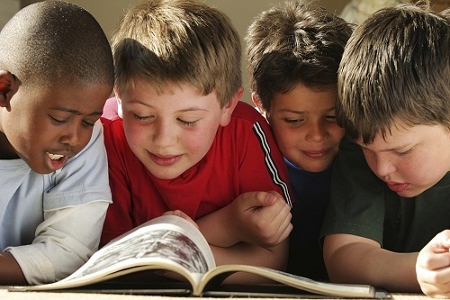 Four young children reading a book together