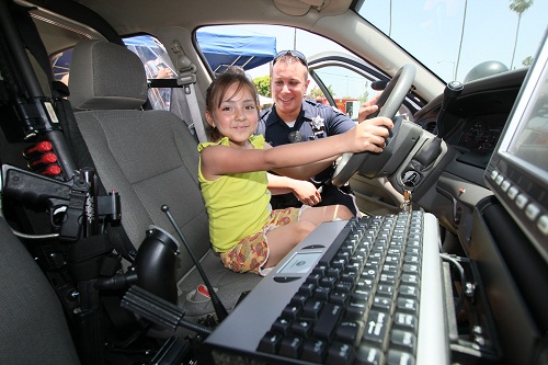 A girl sitting on driver side and a Sherriff standing next to her, posing for a photo