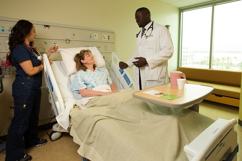 A staff member and doctor standing around a patient's bed as they are examining the patient